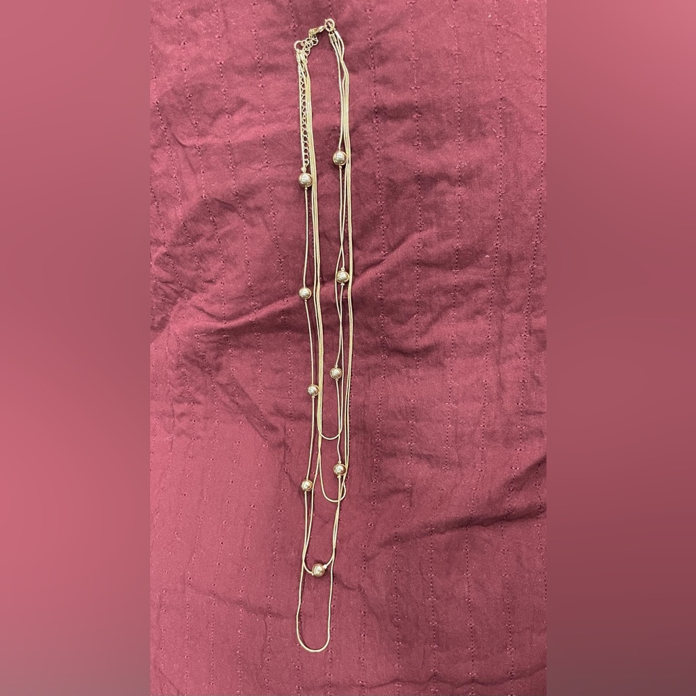 Gold necklace. Four attached strands, one with gold beads.